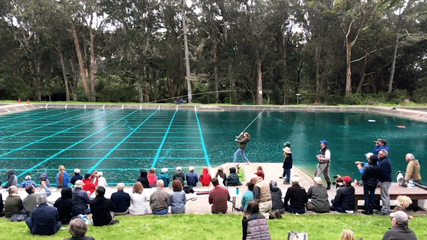 Champion caster Maxine McCormick casts a two-handed fly rod in front of a crowd at San Francisco's Golden Gate Park casting pond