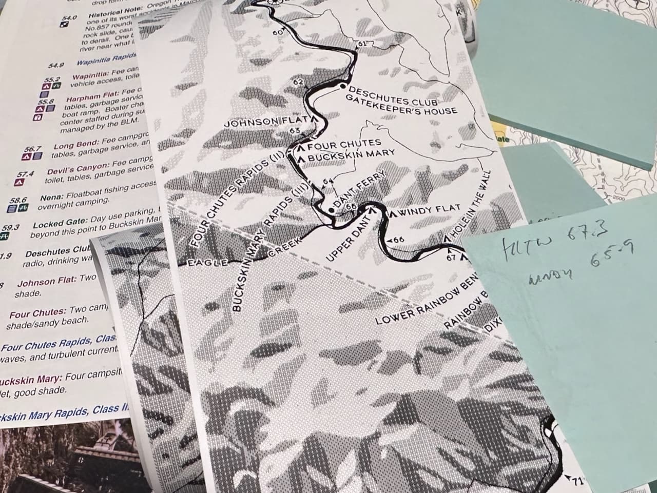 Lower Deschutes River ribbon map spread on a table alongside a Boater's Guide, showing rapids and campsites between river miles 67 and 60