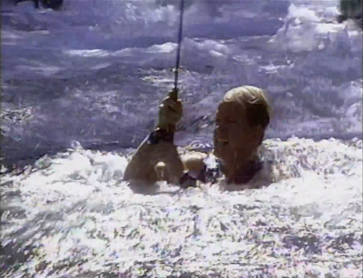 A man floats through a rapid reeling a fly rod