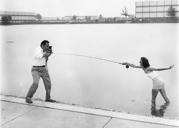Joan Wulff casts a fly rod in a casting pond while having her photograph taken by a male photographer. 